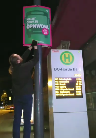 Ein Mitglied eines Plakatierungsteams bringt unser Wahlplakat zum ÖPNV (