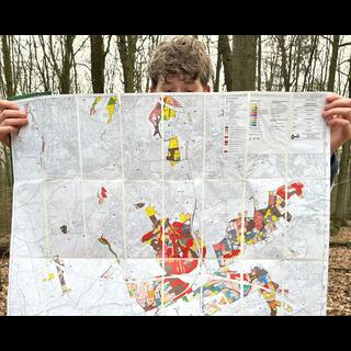 Ein Teilnehmer des Waldspaziergangs hält eine Karte in die Kamera, die den Waldbestand im Stadtgebiet Dortmund zeigt.